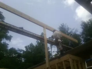 Carpenter setting a ridge beam over a new addition frame — Ice Dam Removal by Roofing Brothers in Guthrie