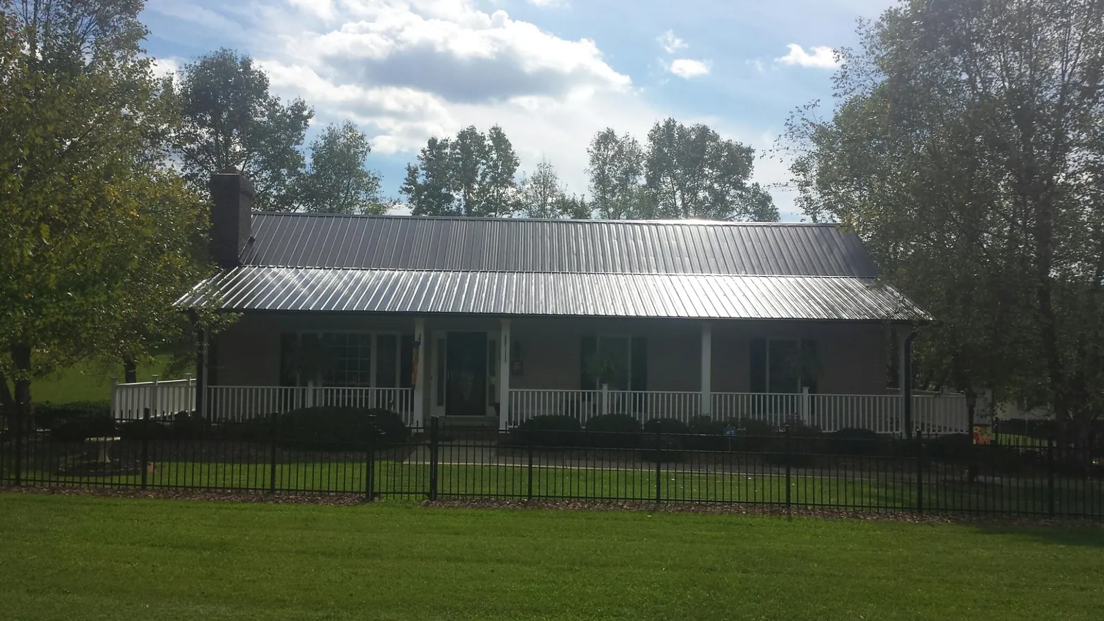 Gray metal roof on a brick ranch with a full width front porch — Gutter Guard Installation work by our crew in Guthrie
