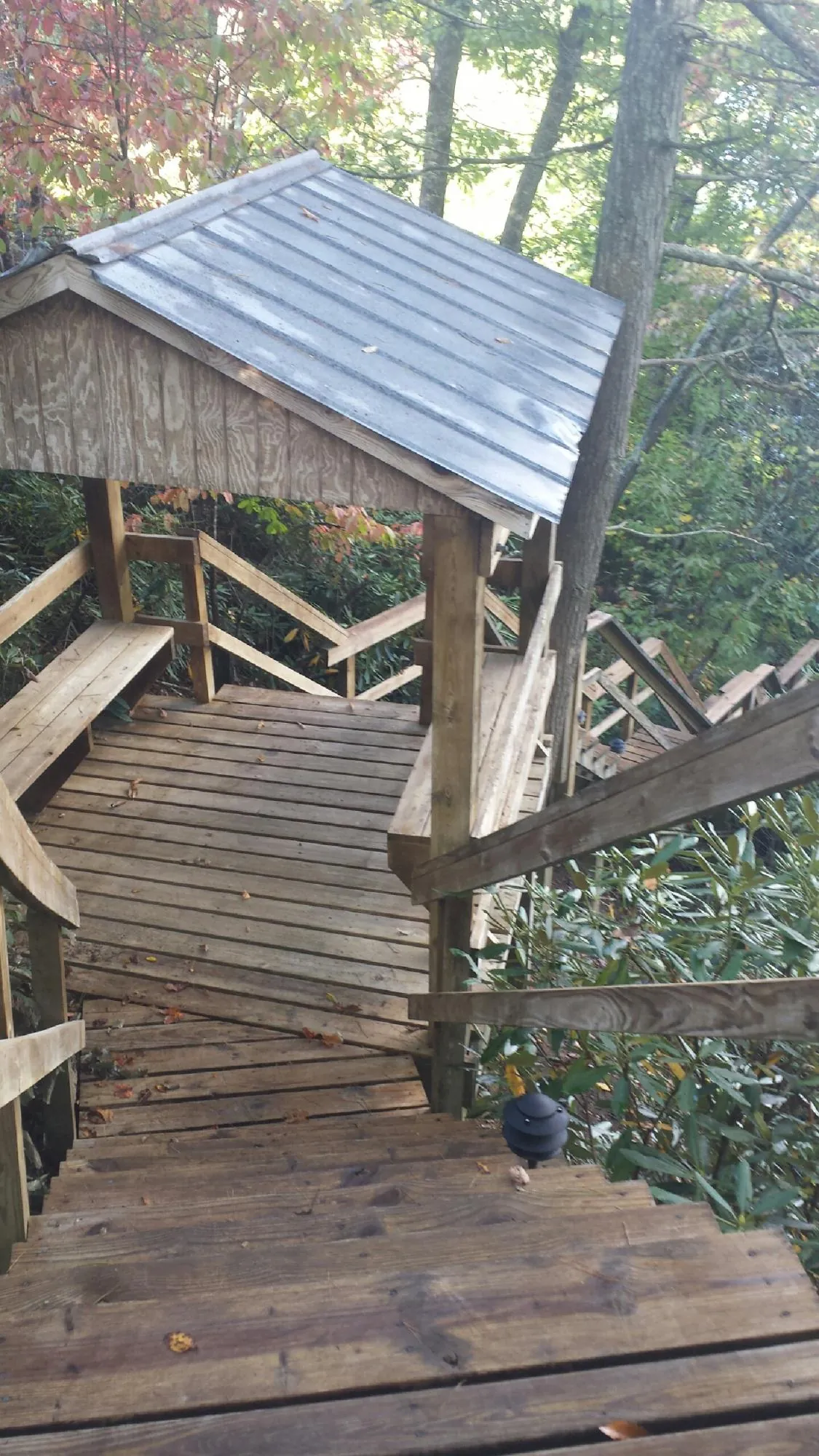 Metal roofed shelter over wooden steps on a wooded walkway — Skylight Repair & Installation work by our crew in Guthrie